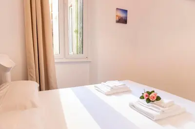 a white bed with towels and a bouquet of flowers on it at LUXURY BABUINO -exclusive apartment in Rome