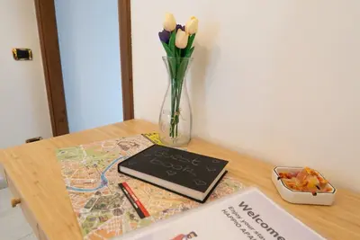 a vase of flowers and a laptop on a table at Happio Apartment in Rome in Rome
