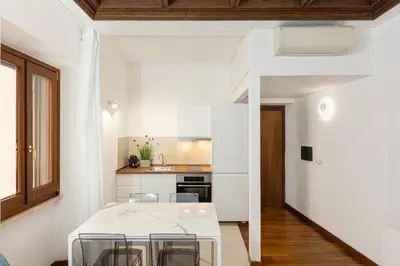 a white kitchen with a table and chairs at Vicolo Trevi Apartment by Rental in Rome in Rome