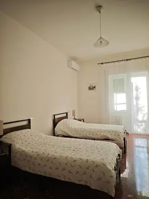 two beds in a white room with a window at Large Apartment in Garbatella Near the Center of Rome in Rome
