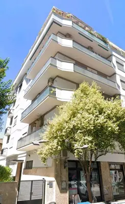 a tall white building with a tree in front of it at Large Apartment in Garbatella Near the Center of Rome in Rome