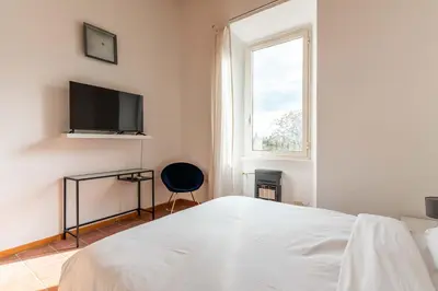 a white bedroom with a bed and a television at Domus Sabelli in Rome