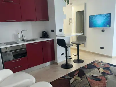 a kitchen with red cabinets and a sink and two chairs at Appartamento Porto di Ripetta in Rome
