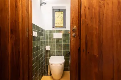 a bathroom with a toilet and a green tiled wall at the secret terrace - navona in Rome