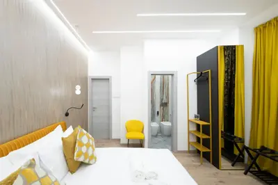 a bedroom with a bed and a yellow chair at Olimpico Luxury Rooms in Rome