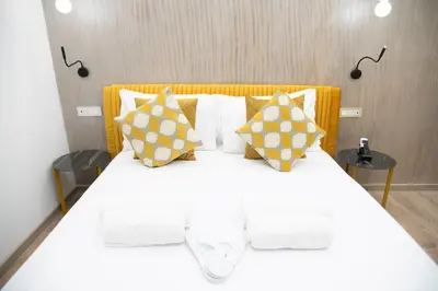 a bedroom with a large white bed with yellow pillows at Olimpico Luxury Rooms in Rome