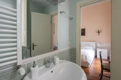 a bathroom with a sink and a mirror and a bed at Vatican Luxury Three Bedroom Apartment in Rome