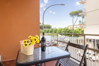 a table with a bottle of wine and flowers on a balcony at Atelier Latino in Rome
