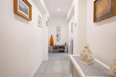 a hallway with white walls and a tile floor with a lantern at Jubilee Metro A 15 minutes from the Colosseum in Rome