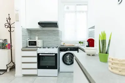 a kitchen with a washing machine and a microwave at Jubilee Metro A 15 minutes from the Colosseum in Rome