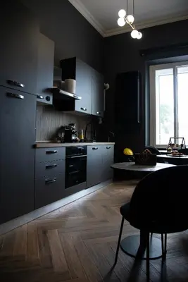 a kitchen with black cabinets and a wooden floor at One of one Experiences - LOVE SPA SUITE in Rome