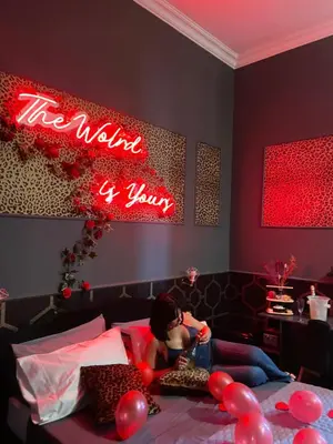 a girl laying on a bed with a neon sign at One of one experiences - LOVE ROOM in Rome