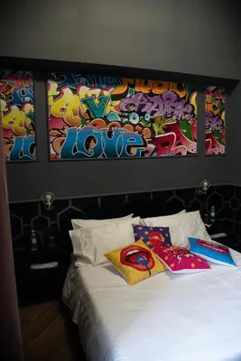 a bed with two pillows and a painting on the wall at One of one experiences - ART ROOM in Rome