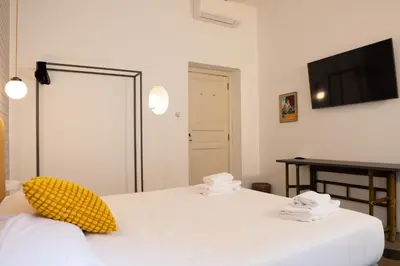 a bedroom with two beds and a television on the wall at 101 Flats Candia's Suites in Rome
