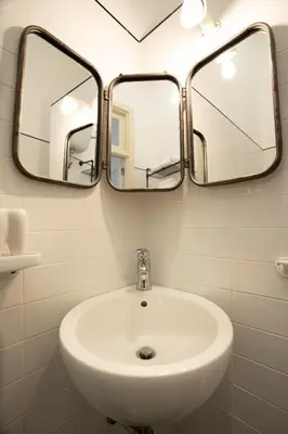 a bathroom with a white sink and three mirrors at 101 Flats Candia's Suites in Rome