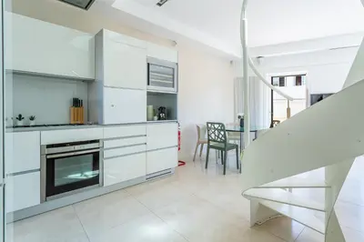 a kitchen with white cabinets and a table with chairs at iFlat Spanish Steps Unique Panoramic Penthouse in Rome