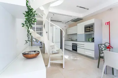 a staircase in a kitchen with white cabinets at iFlat Spanish Steps Unique Panoramic Penthouse in Rome