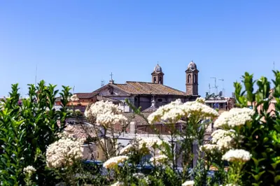 a building with a clock tower in the background with white flowers at iFlat Spanish Steps Unique Panoramic Penthouse in Rome
