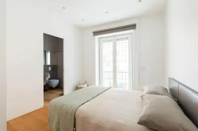 a white bedroom with a bed and a window at Popolo Design Apartment by RomeLoft in Rome