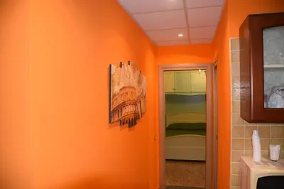 a hallway with an orange wall with a picture on it at Appartamenti Romolo E Remo in Rome