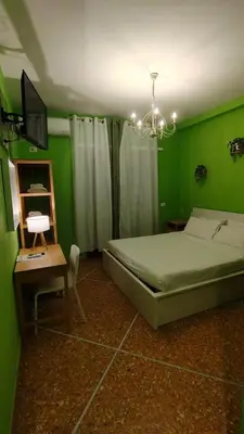 a green bedroom with a bed and a table and a television at Appartamenti Romolo E Remo in Rome