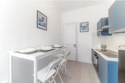 a white kitchen with a white counter and stools at Qflat Elegant Palumbo Vatican in Rome