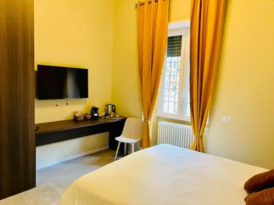 a bedroom with a bed and a desk with a television at Aura Roma in Rome