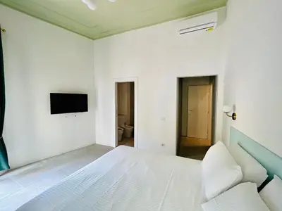 a white bedroom with a white bed and a tv at Aura Roma in Rome