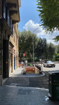 a street with a car driving past a building at Casa di latta in Rome