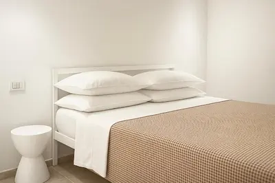 a white bedroom with a bed with four pillows at NERI Vatican Suite in Rome
