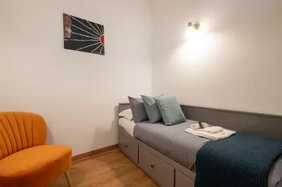 a bedroom with a bed and a orange chair at Frattina Cozy Flat Spanish Steps in Rome