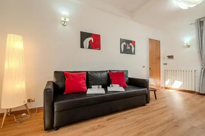 a black leather couch in a living room with red pillows at Frattina Cozy Flat Spanish Steps in Rome