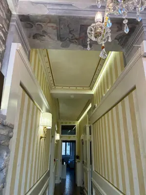 a hallway with yellow and white striped walls and a chandelier at Piazza Venezia appartamento con vista in Rome