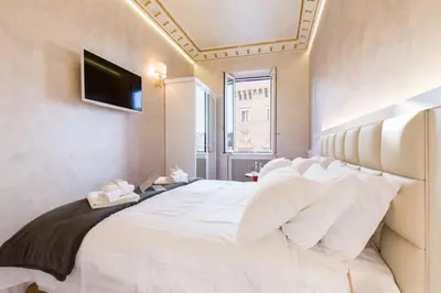 a bedroom with a large white bed with a television on the wall at Piazza Venezia appartamento con vista in Rome