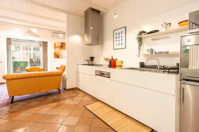 a kitchen with white cabinets and an orange chair in it at Casa Verde - Luxury apartment in Trastevere in Rome