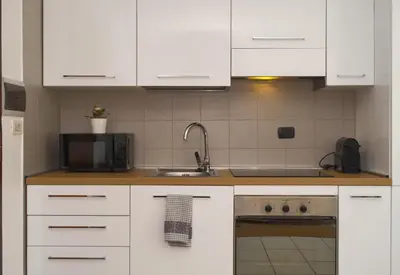 a kitchen with white cabinets and a sink and a microwave at Duplex Chic in zona trendy in Rome