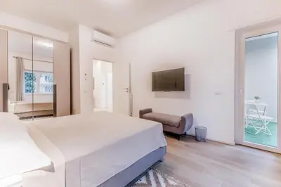 a white bedroom with a large bed and a chair at Domus urbe San Paolo in Rome
