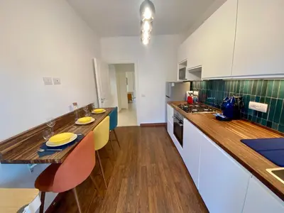 a kitchen with white cabinets and a wooden counter top at Leone's rooms - House for 6 people in Rome