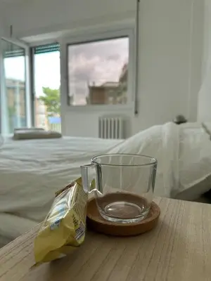 a glass cup sitting on a wooden table next to a bed at Leone's rooms - House for 6 people in Rome