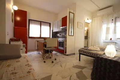 a living room with a table and a kitchen at Rouge studio - 10 min from Vatican in Rome