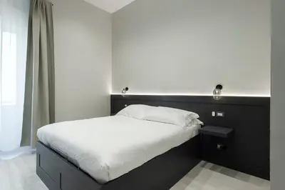 a bed with a black headboard and white sheets at Maison Ottaviano -Vatican- in Rome