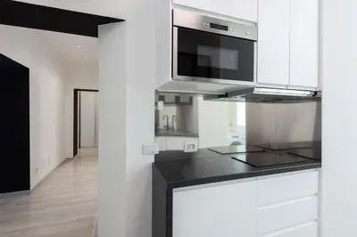 a kitchen with white cabinets and a black counter top at Maison Ottaviano -Vatican- in Rome