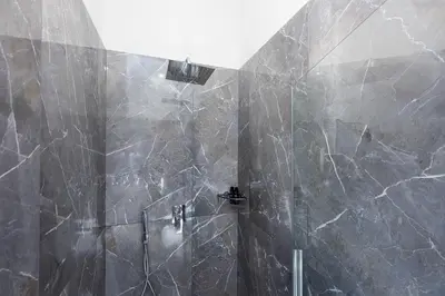a bathroom with a shower with black marble walls at Iron Monti Coliseum in Rome
