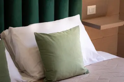 a bed with white pillows and a green curtain at Iron Monti Coliseum in Rome