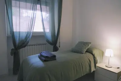 a bedroom with a bed with blue curtains and a window at Daniela's Home vicino a Metro A e Vaticano in Rome
