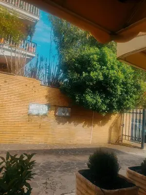a yellow brick wall with trees and plants on it at Daniela's Home vicino a Metro A e Vaticano in Rome
