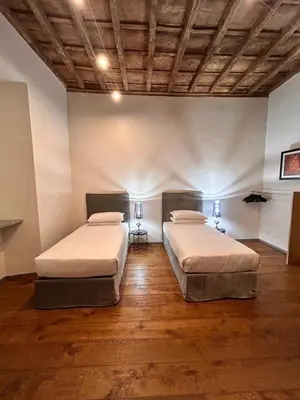 two beds in a large room with wooden floors at Fontana di Trevi Roma Luxury in Rome