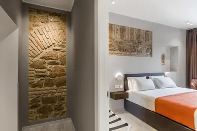 a bedroom with a bed and a stone wall at Trastevere Travertino Suite in Rome