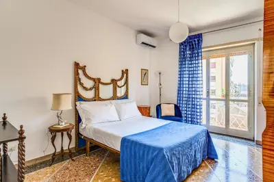 a bedroom with a bed with a blue bedspread and a window at AMORE MIO - Art House in Rome