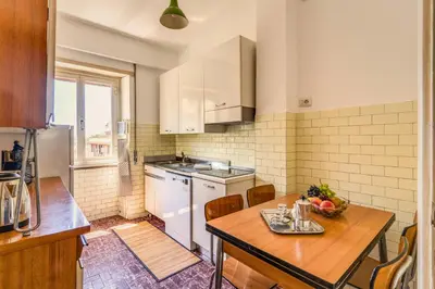a kitchen with white appliances and a wooden table at AMORE MIO - Art House in Rome
